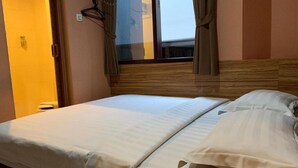 A hotel room with a bed, a window with curtains, and a wooden headboard. - Rumah Shinta (Jakarta)