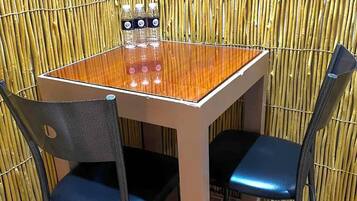 A small dining area with a bamboo wall, a wooden table, and two blue chairs.