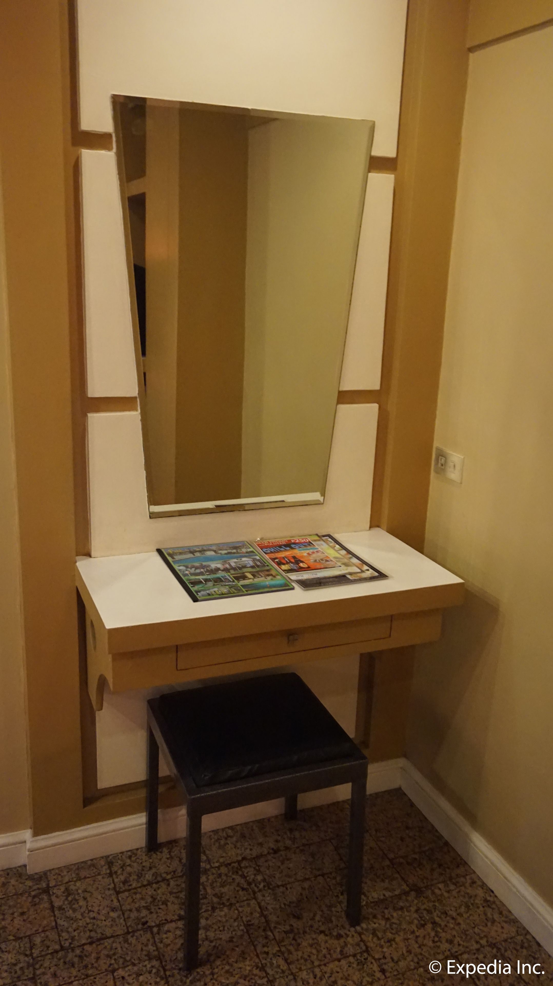 A small vanity with a mirror, a magazine holder, and a stool.