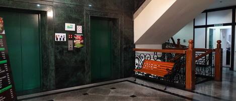 A lobby with a marble floor, a wooden bench, and a staircase.