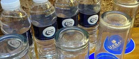 A collection of water bottles and glasses with the "Urban Travellers Hotel" logo on blue coasters.