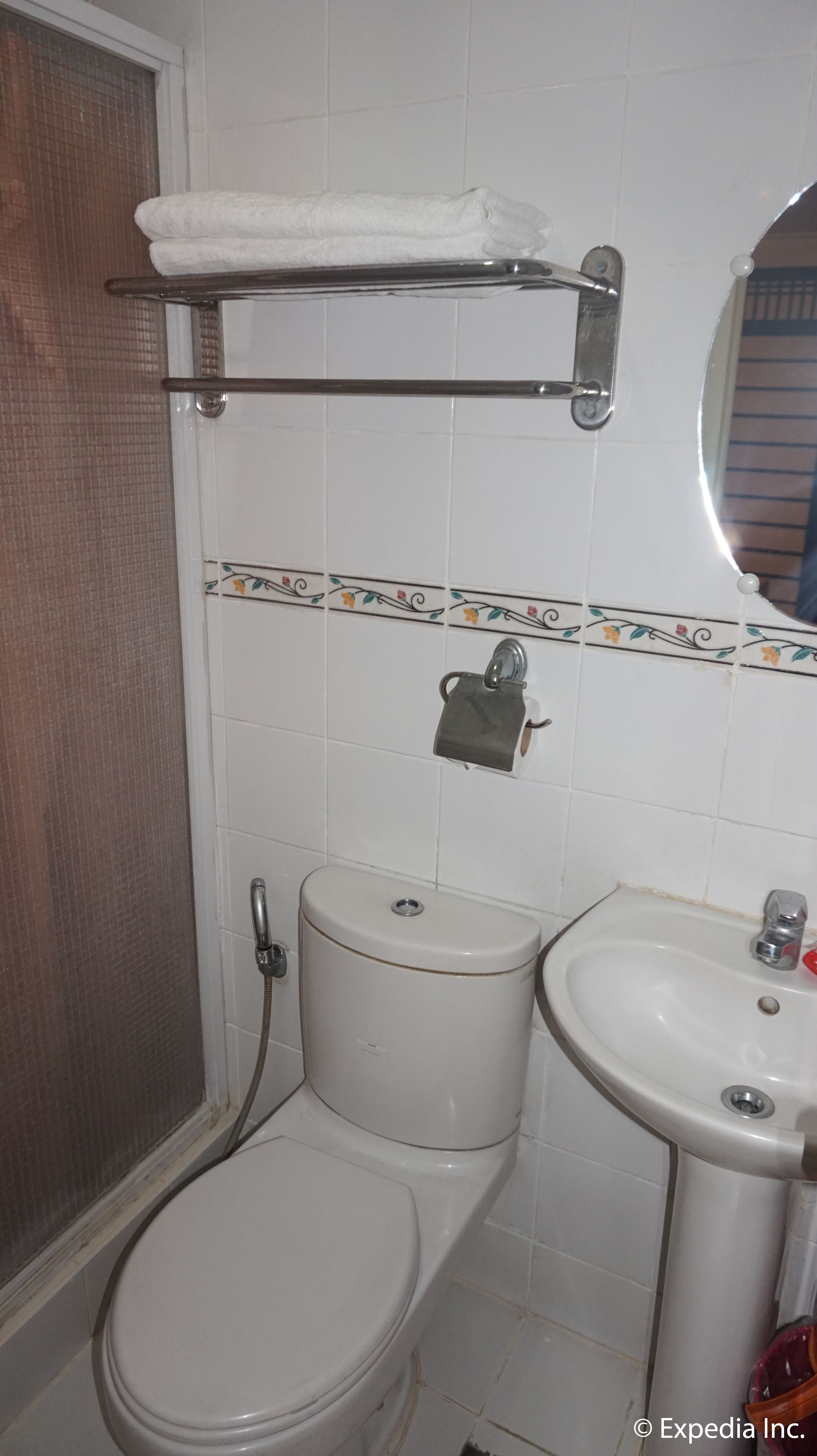Un baño con inodoro, lavamanos y perchero para toallas.