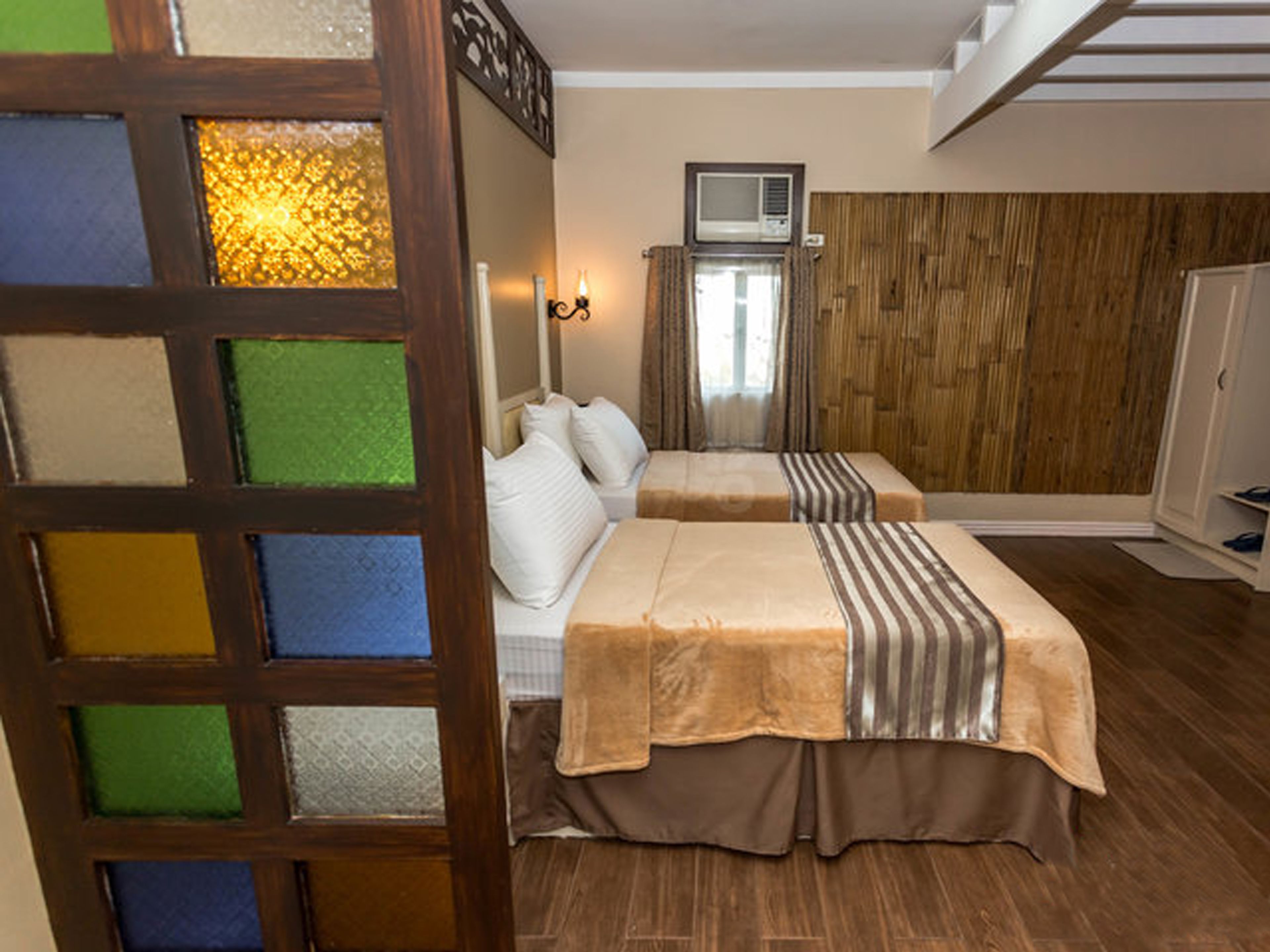 Habitación de hotel con dos camas, un televisor y una pared de madera.