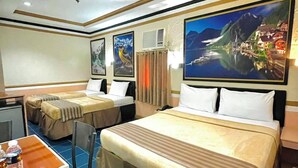 Habitación de hotel con dos camas, un escritorio, sillas y obras de arte en las paredes.