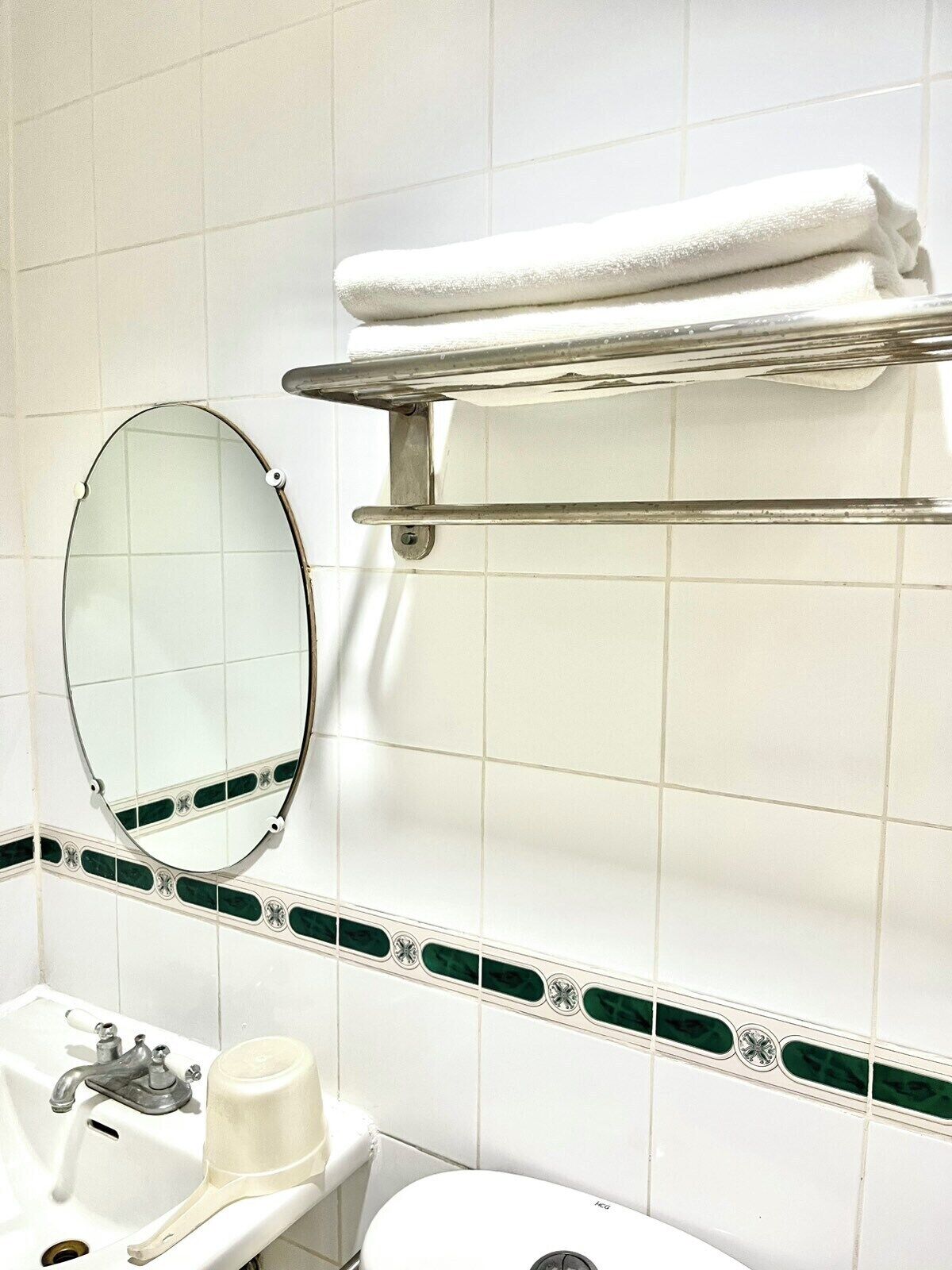 Une salle de bain avec un lavabo blanc, un miroir, un porte-serviettes et des toilettes.