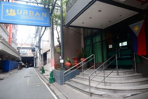 A hotel entrance with a sign for 'URBAN TRAVELLERS HOTEL' and a staircase leading up to the entrance.
