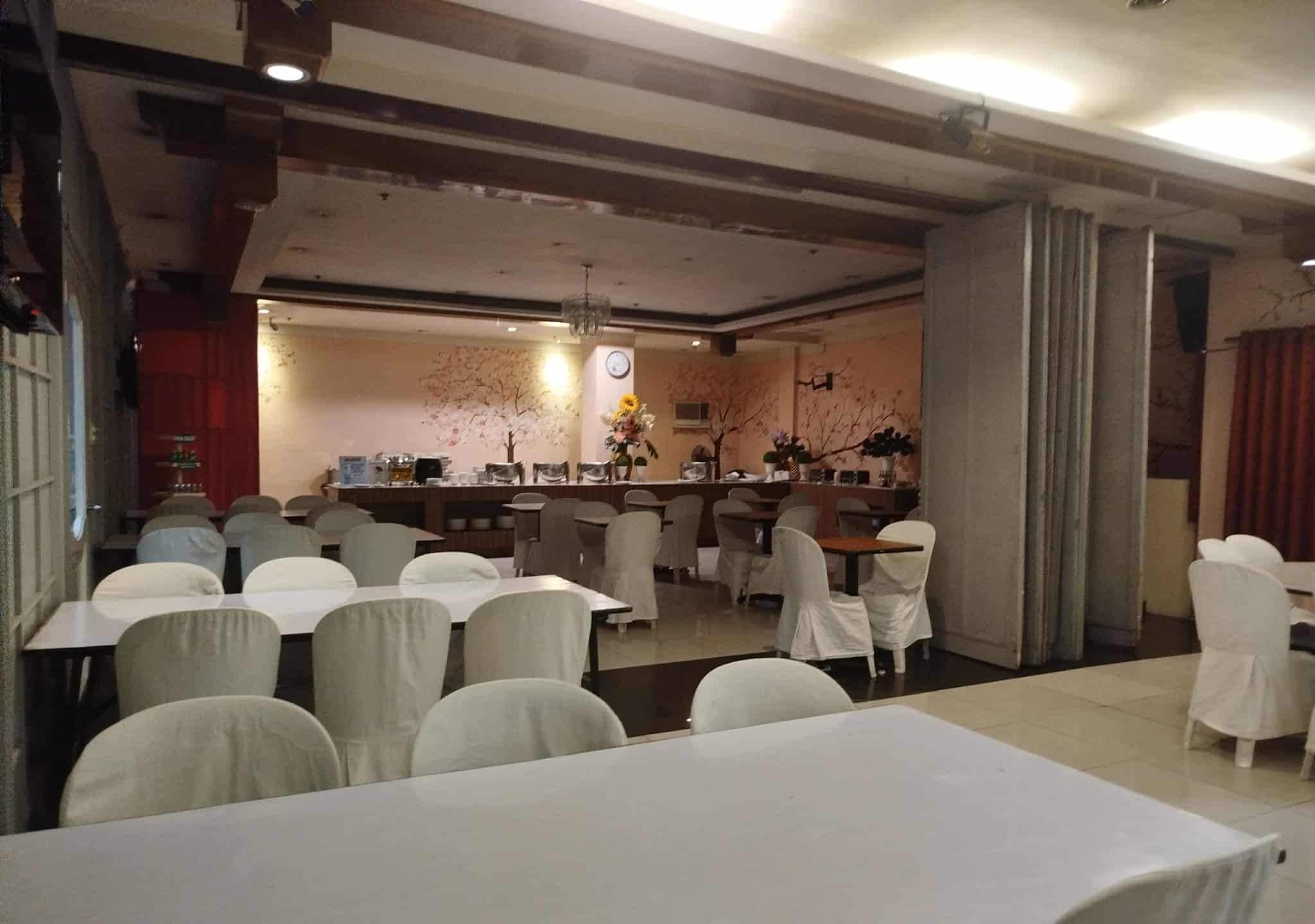 A restaurant with multiple tables and chairs, a bar area, and decorative elements like flowers and wall art.