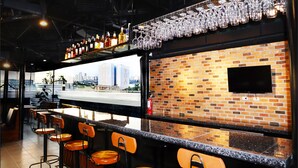 Zona de bar con pared de ladrillo, televisor y vista panorámica de la ciudad.