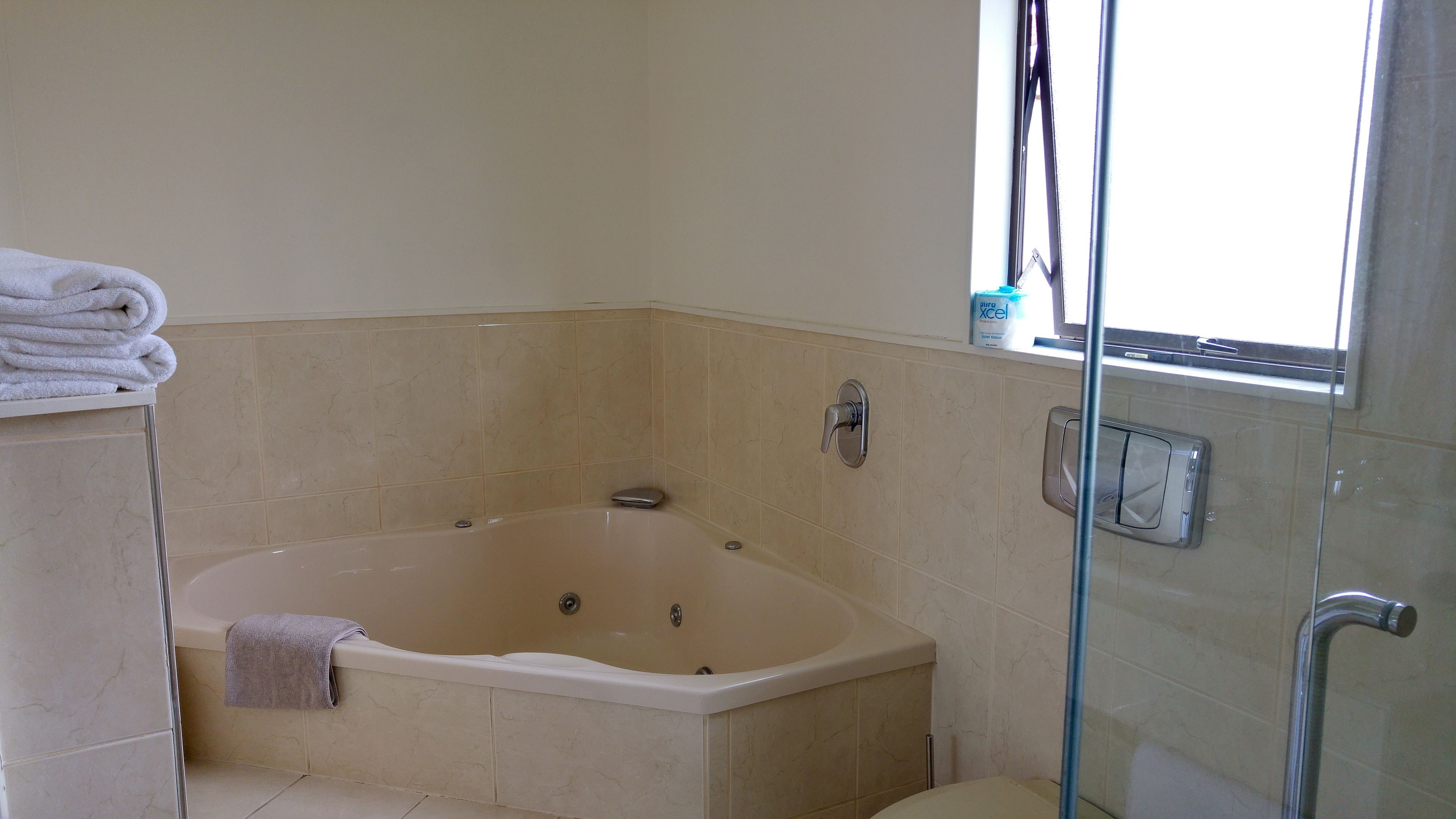 Un baño con bañera, cabina de ducha de vidrio y retrete.