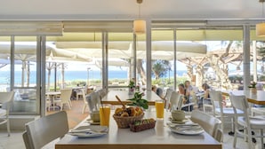 Un restaurante con terraza, amplias ventanas y vista al océano.