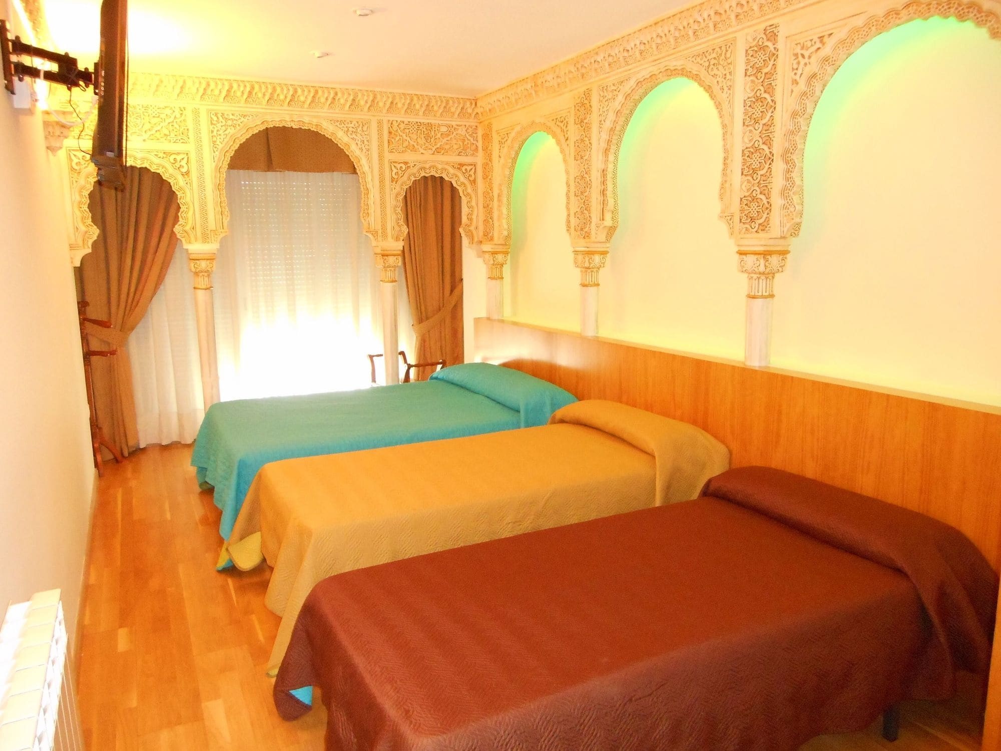 Ein Hotelzimmer mit drei Betten, aufwendigen Wandverzierungen und einem hölzernen Kopfteil.