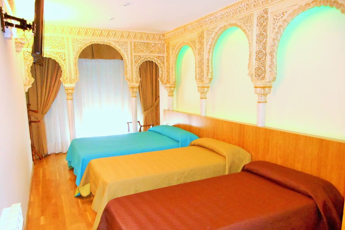 A hotel room with two beds, ornate arches, and a wooden headboard.