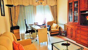 Una sala de estar con sofá, sillón, mesa de centro y aparador.