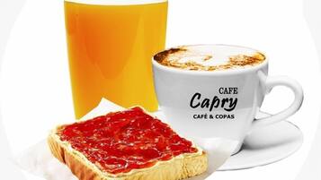 Un verre de jus d’orange, une tasse de café et une tranche de pain grillé avec de la confiture.