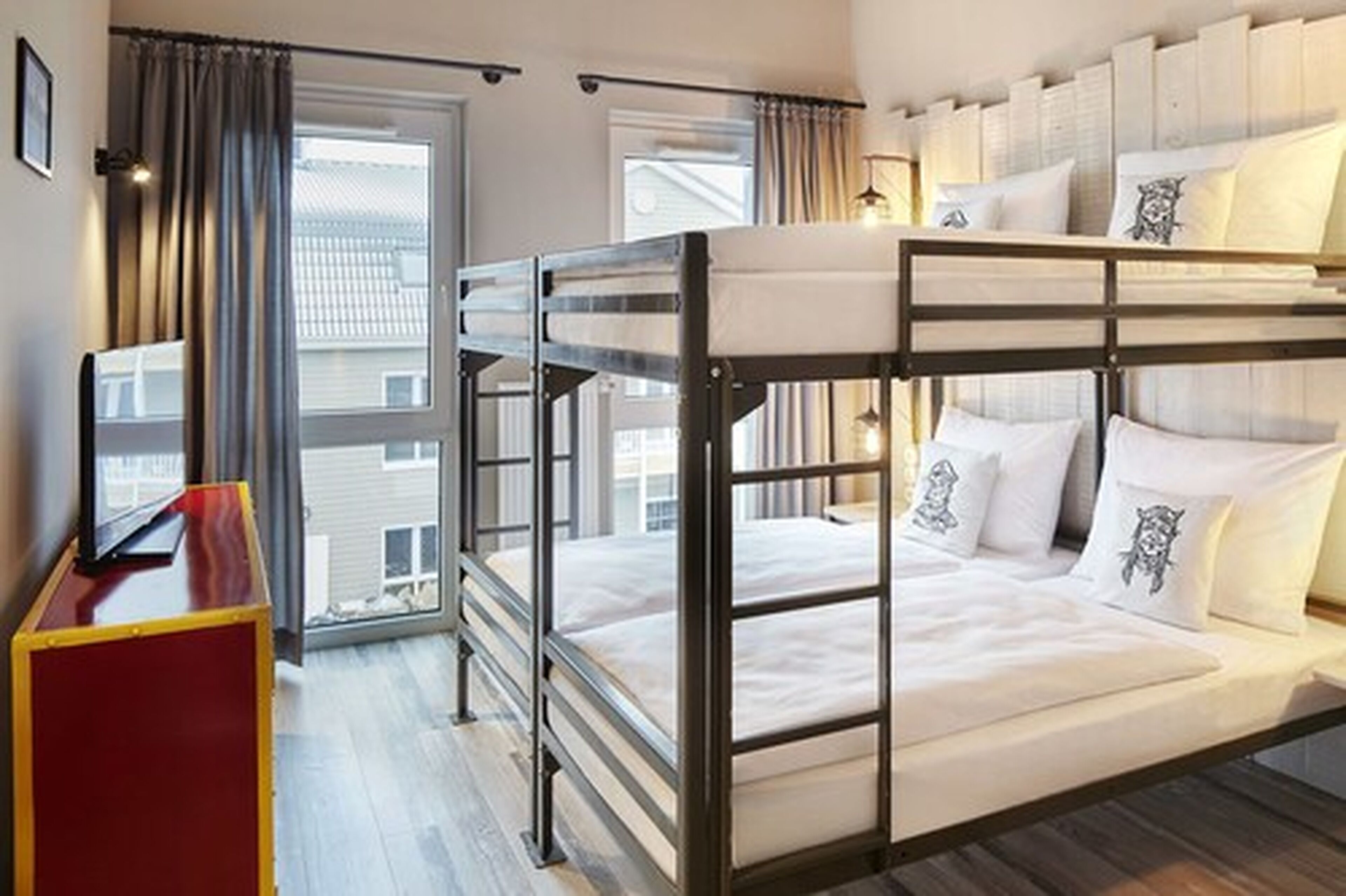 Une chambre avec un lit superposé, un bureau et une fenêtre avec des rideaux.