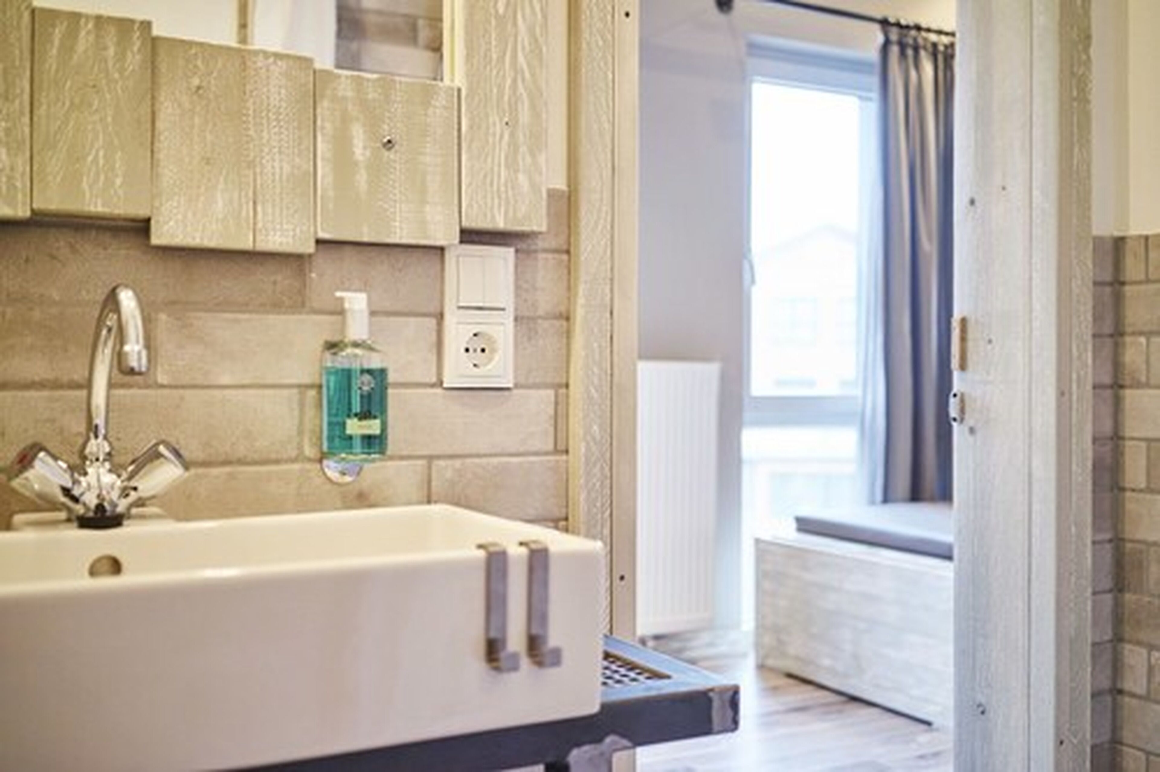 A bathroom with a white sink, a mirror, and a bottle of hand soap.