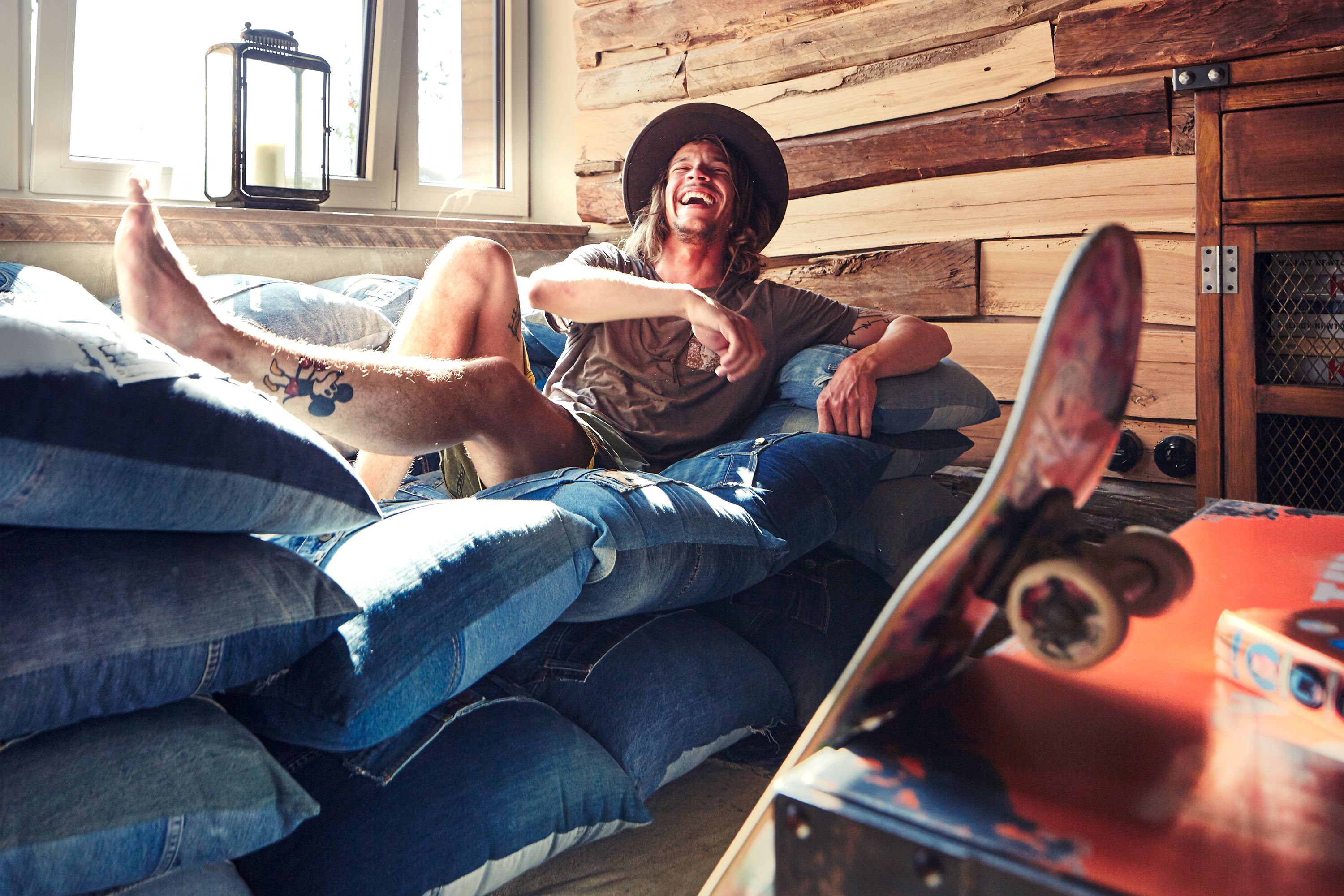 A person lying on a bed with a skateboard nearby.