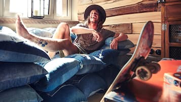 A person lying on a bed with a skateboard nearby.