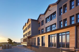 Un edificio de varios pisos con un diseño moderno, que cuenta con grandes ventanales y un techo plano.