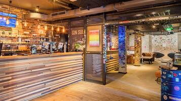 A bar area with wooden slats, a seating area with couches, and a wall decorated with stickers.