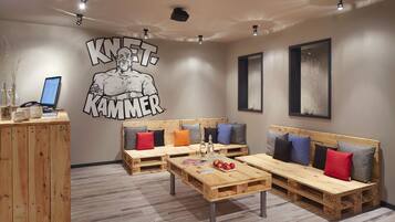 Un área de descanso moderna con muebles de madera, un mural grande en la pared y una computadora en un escritorio.