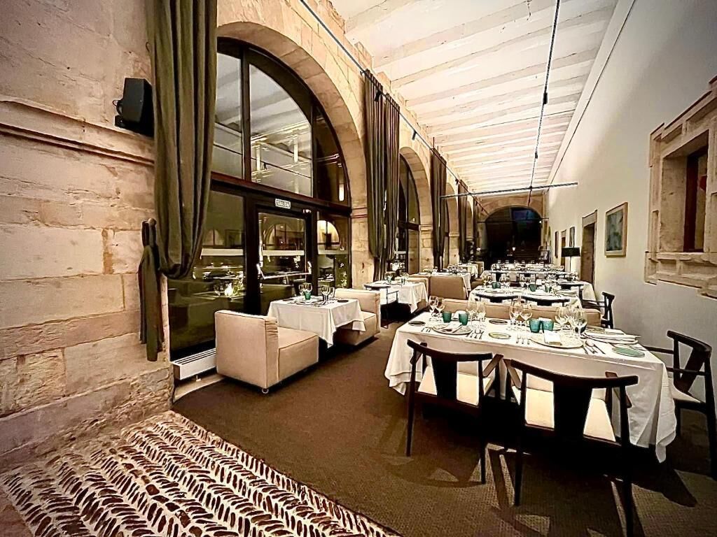 A restaurant with tables set for dining, large windows, and a patterned carpet.