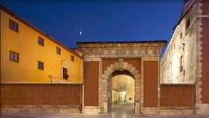 A historic building with an arched entrance, a courtyard, and a moon in the sky. - Hotel Real Colegiata San Isidoro (León)