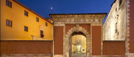 A historic building with an arched entrance, a courtyard, and a moon in the sky.