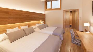 Een hotelkamer met twee bedden, een houten hoofdeinde, een bureau met een stoel en een raam.