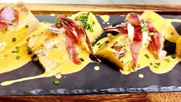 Un plato con carne en rodajas y salsa cremosa, adornado con cebollines sobre un plato oscuro.