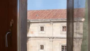 Una ventana con vistas a un edificio de techo con tejas y ventanas de arco.