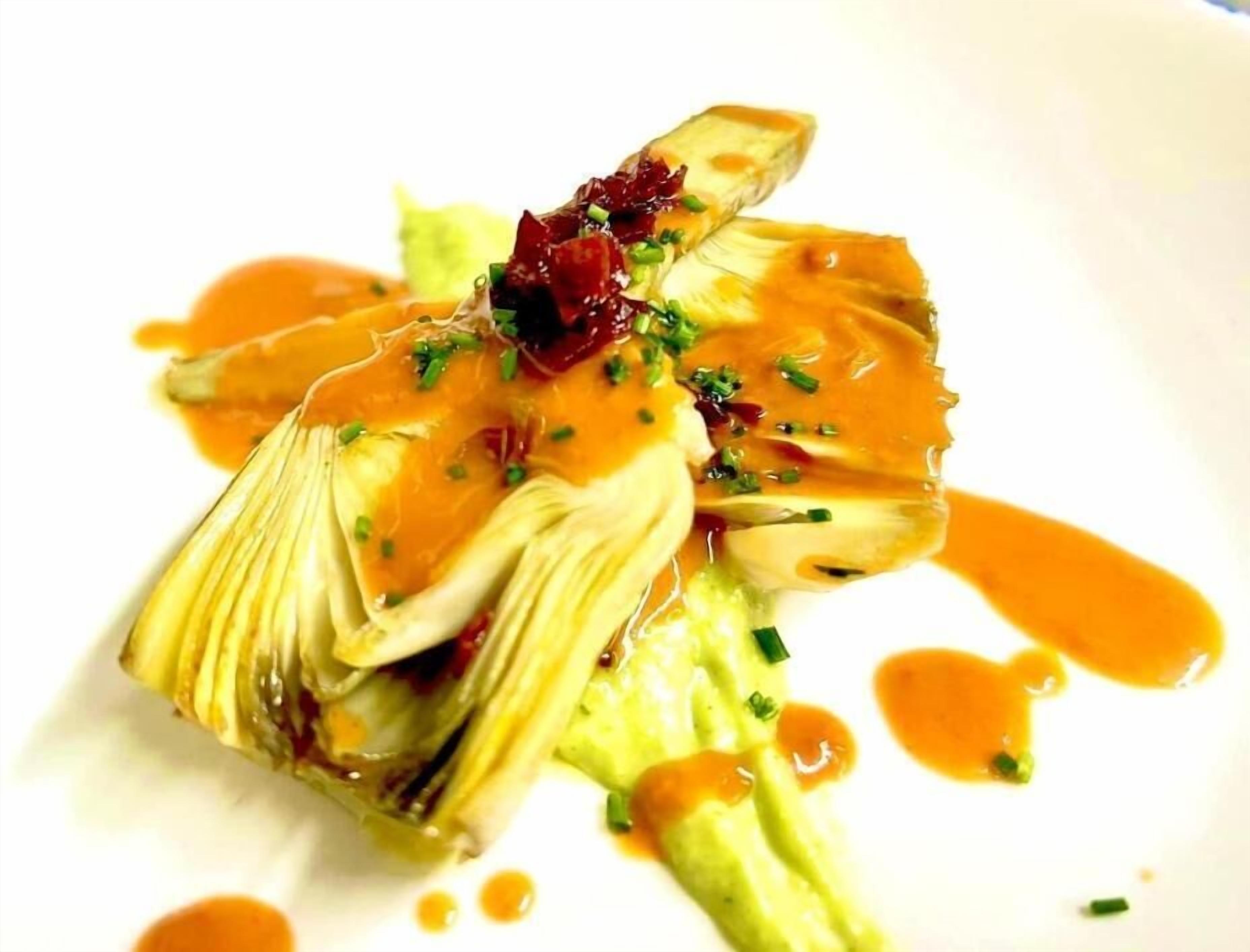 A dish with artichoke and sauce on a white plate.