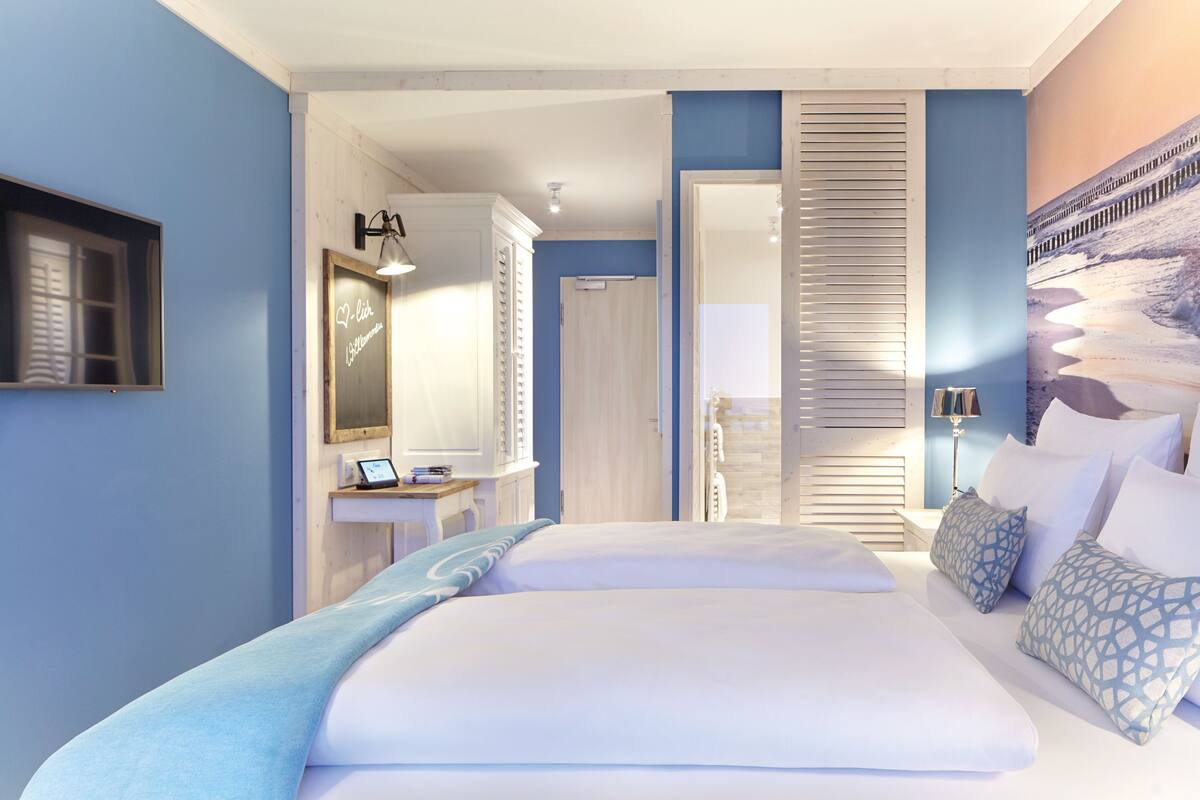 A bedroom with a large bed, a bedside table, a mirror, and a wardrobe.
