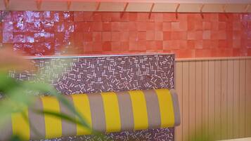 Interior de restaurante con un letrero de neón que dice 'That's Amore', una pared con diseño y un cojín a rayas en un banco.