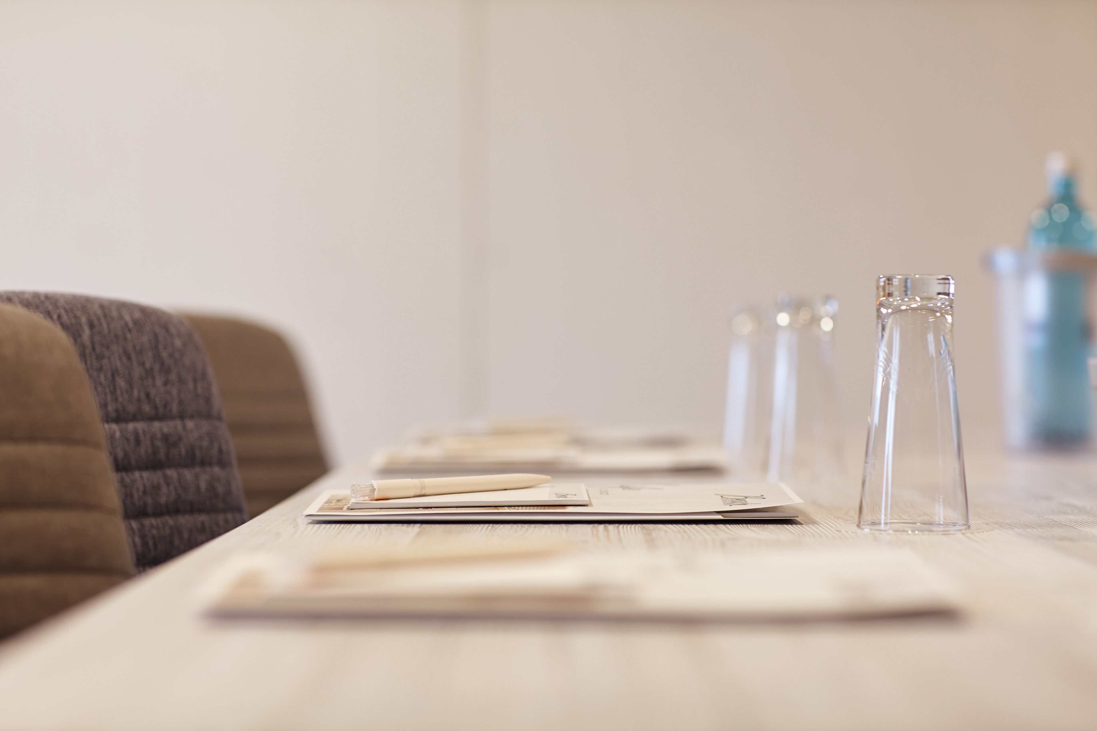 A neatly arranged table with clear glass bottles, a menu, and a pen, suggesting a dining area in a hotel.