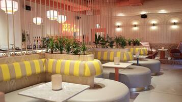 A modern interior with striped seating, tables, and hanging lights.