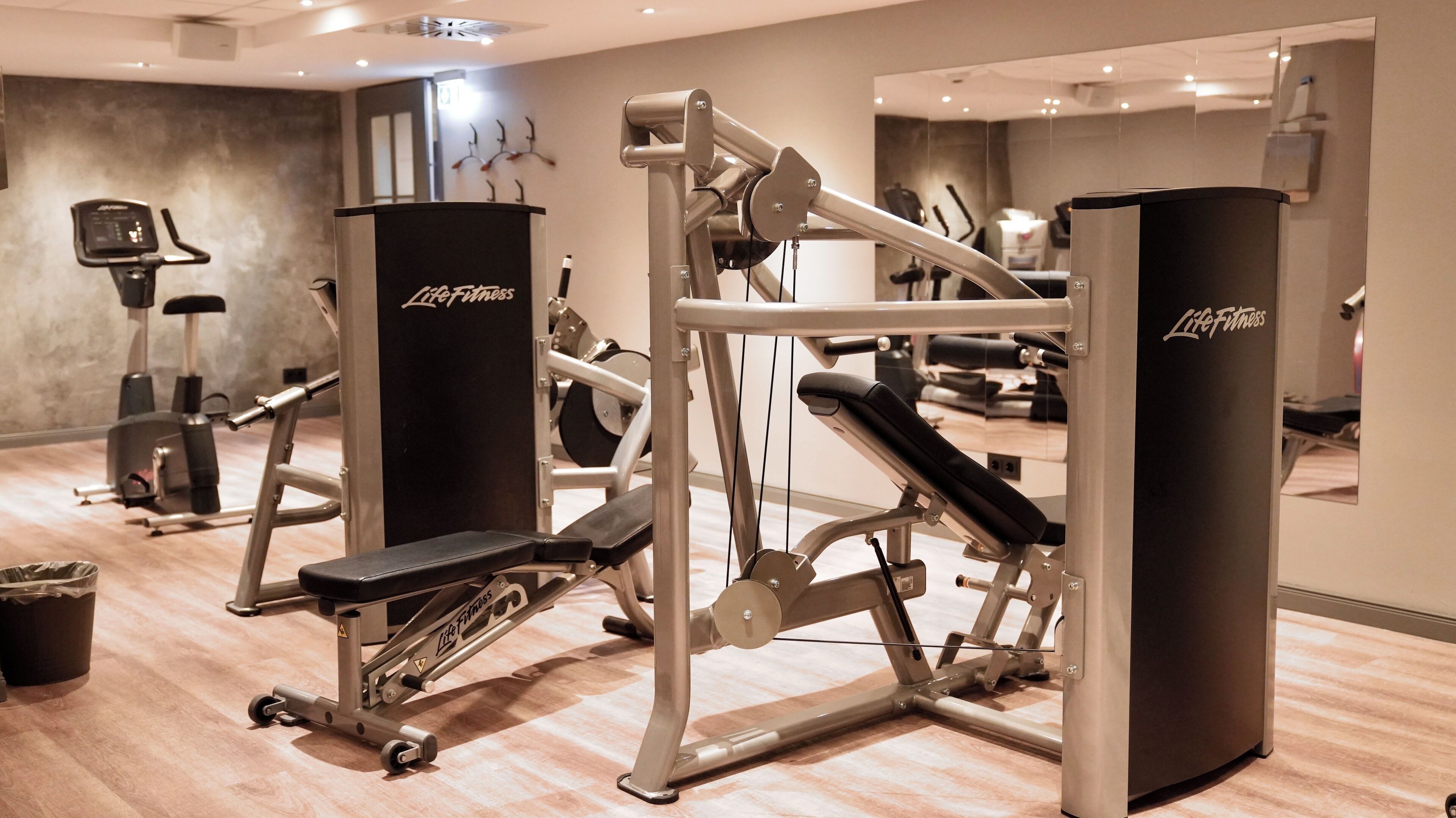 Une salle de sport équipée de divers appareils d’exercice, notamment un tapis de course, un vélo elliptique et des appareils de musculation.