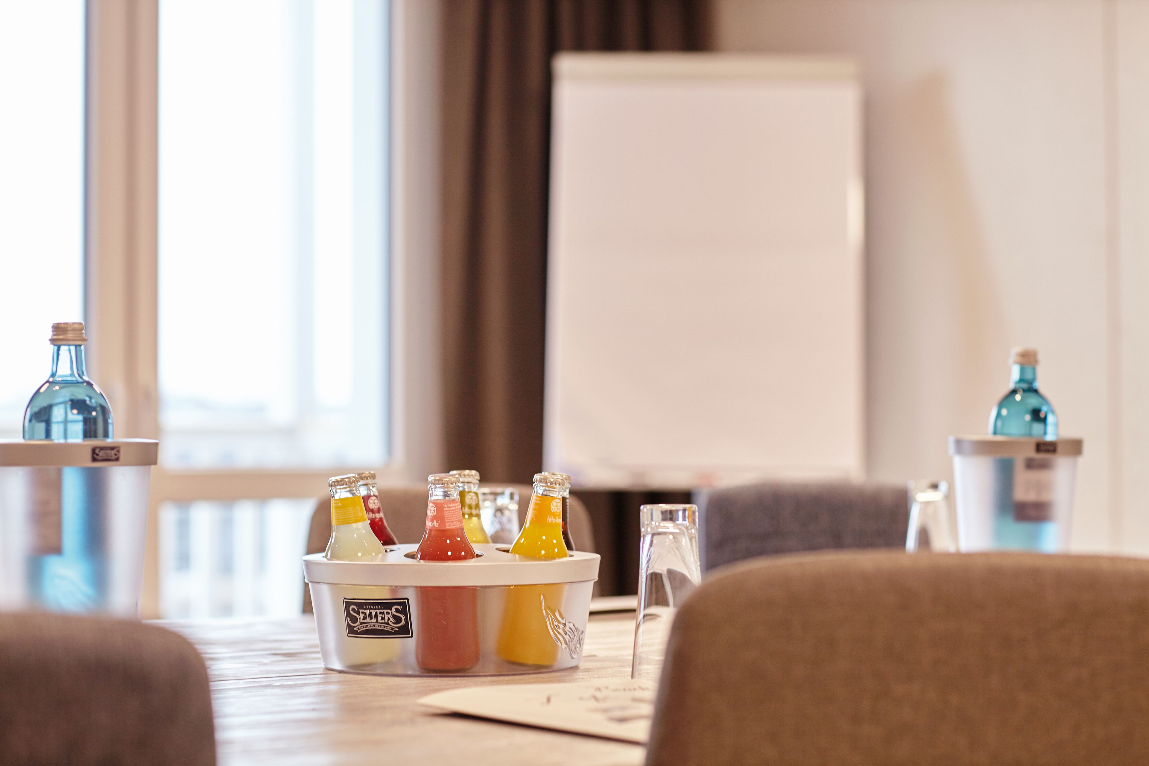 Et hotelværelse med et minibar fyldt med forskellige drikkevarer og en whiteboardtavle.