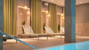 Un área junto a la piscina con sillones de descanso, una piscina y lámparas de mimbre colgantes.