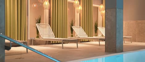 A poolside area with lounge chairs, a pool, and hanging wicker lamps.