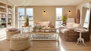Una sala de estar acogedora con un ventanal grande, una estantería, un sofá cómodo y una mesa de centro.