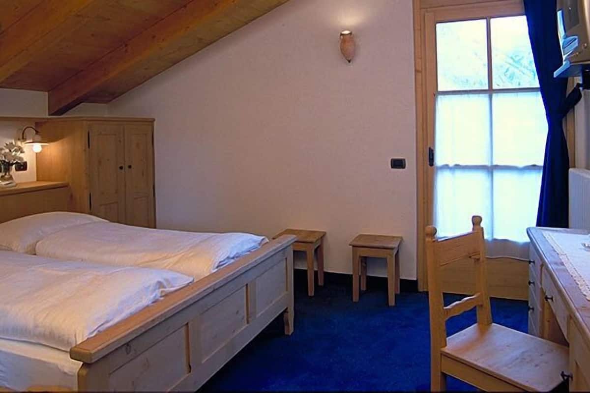 Un dormitorio con una cama de madera, un escritorio pequeño y una silla.