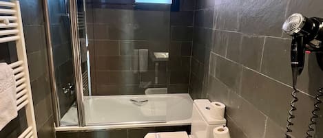 Un baño moderno con ducha de vidrio, bañera y retrete.