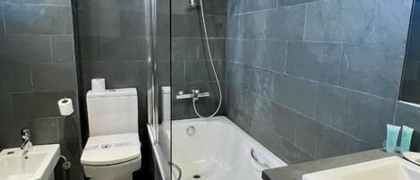 Un baño moderno con ducha, inodoro, bidé y dos lavamanos.