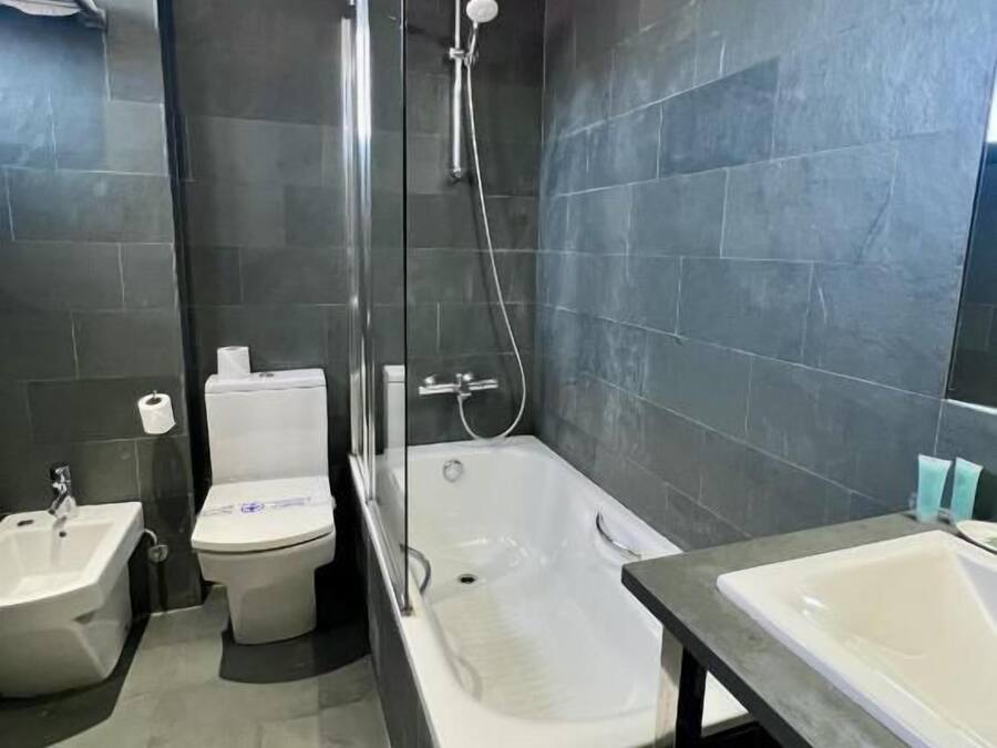 A modern bathroom with a shower, toilet, bidet, and two sinks.