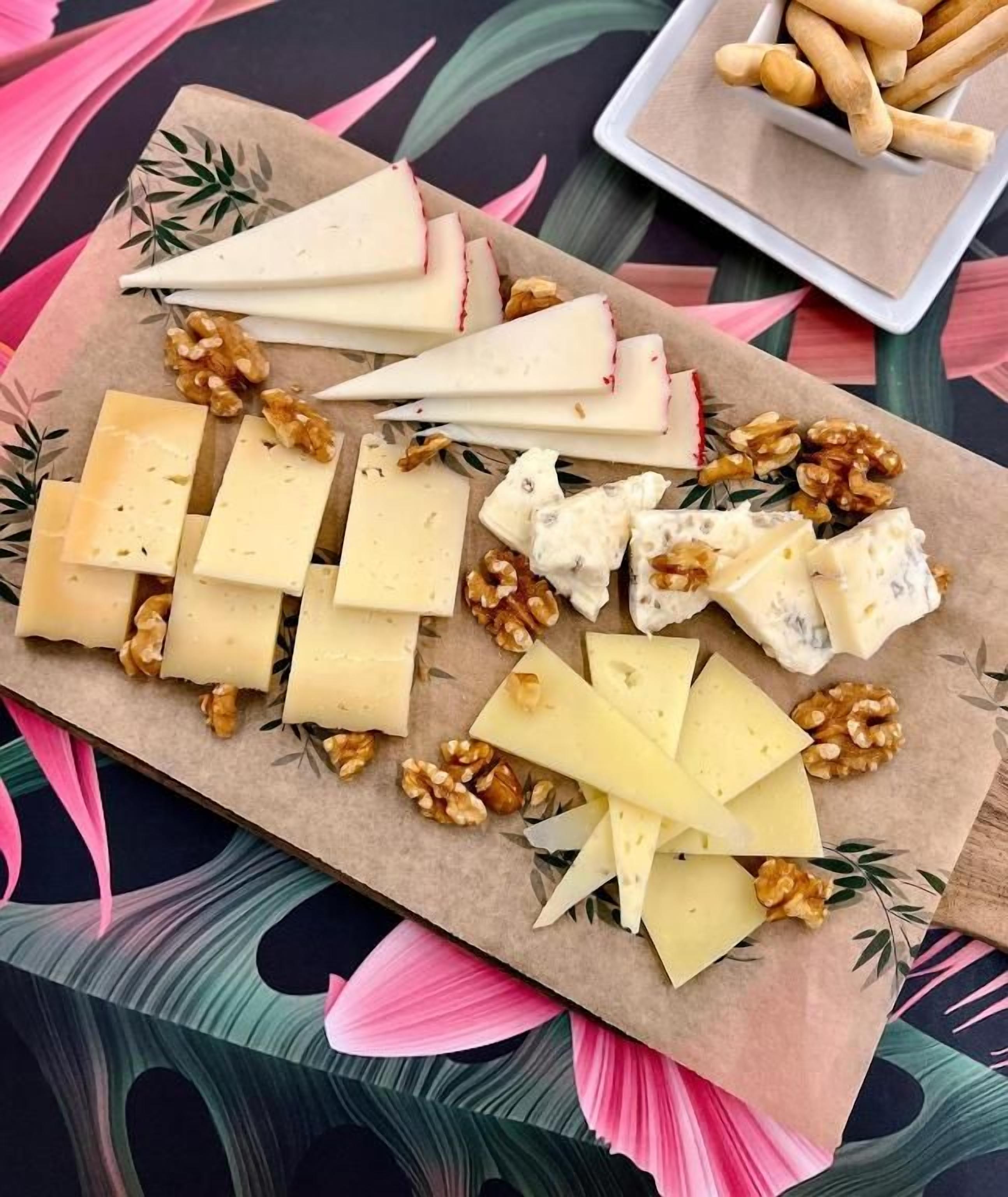 Une planche de fromages avec différents types de fromages et des noix, posée sur une table.