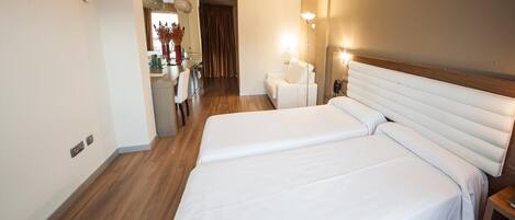Una habitación de hotel con dos camas, una zona de estar y un comedor.