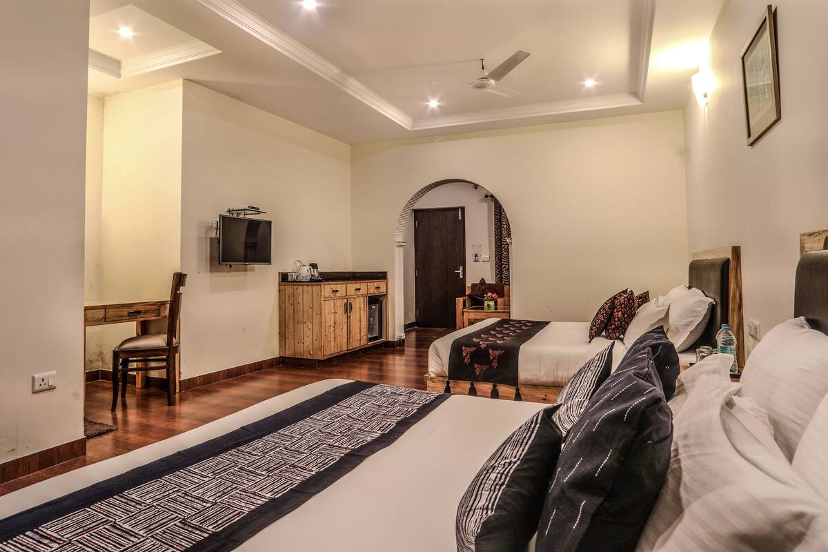 A hotel room with a bed, a desk, a chair, a TV, and a wardrobe.