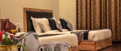 A hotel room with a bed, pillows, a wooden headboard, a green mug with flowers, and two white mugs with 'Hotel Sun Grace' text.