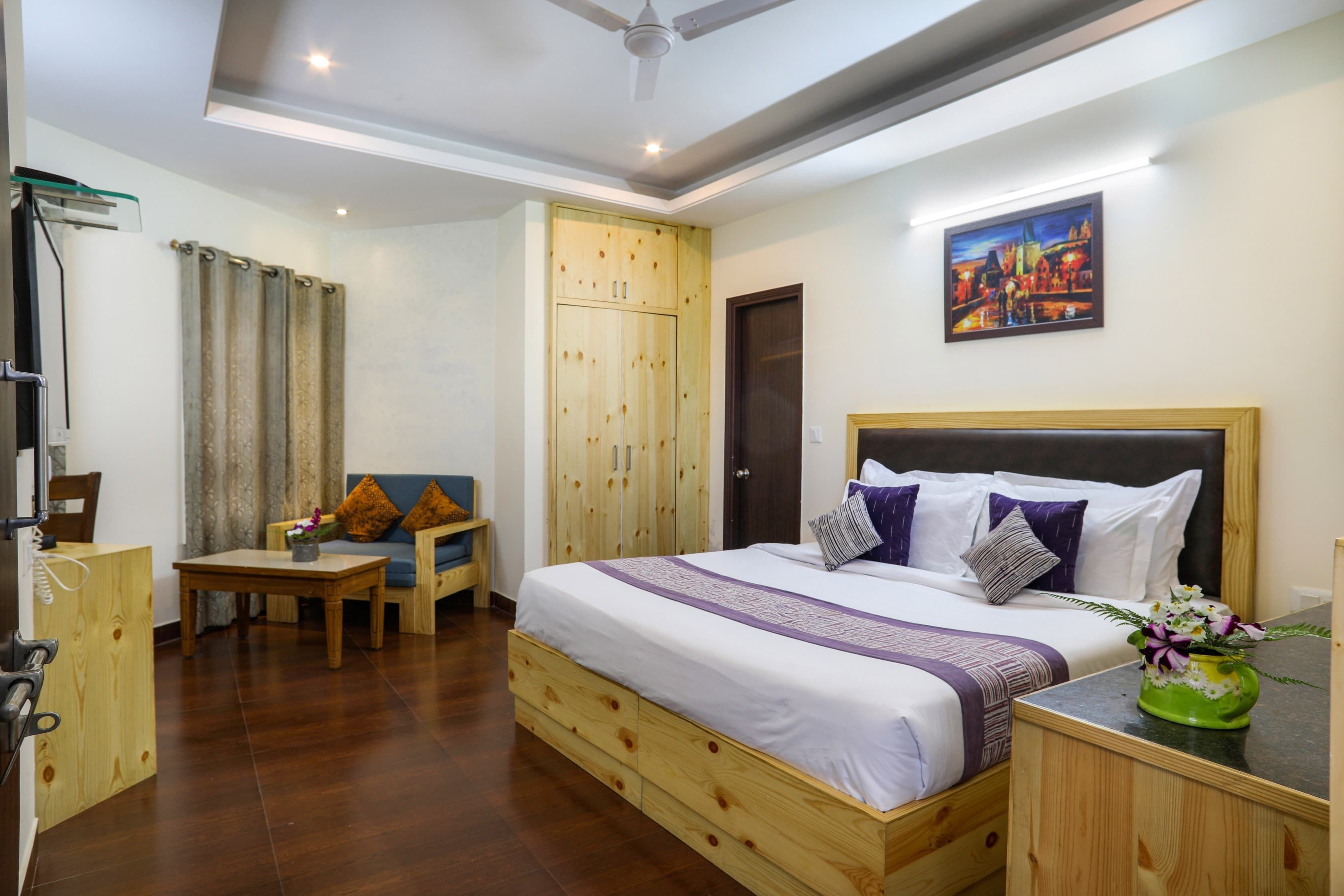 Een hotelkamer met een bed, een bureau, een stoel, een kledingkast en een schilderij aan de muur.